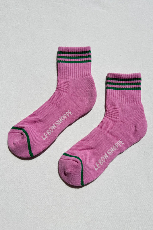 Pink socks with black and green stripes on a light gray background