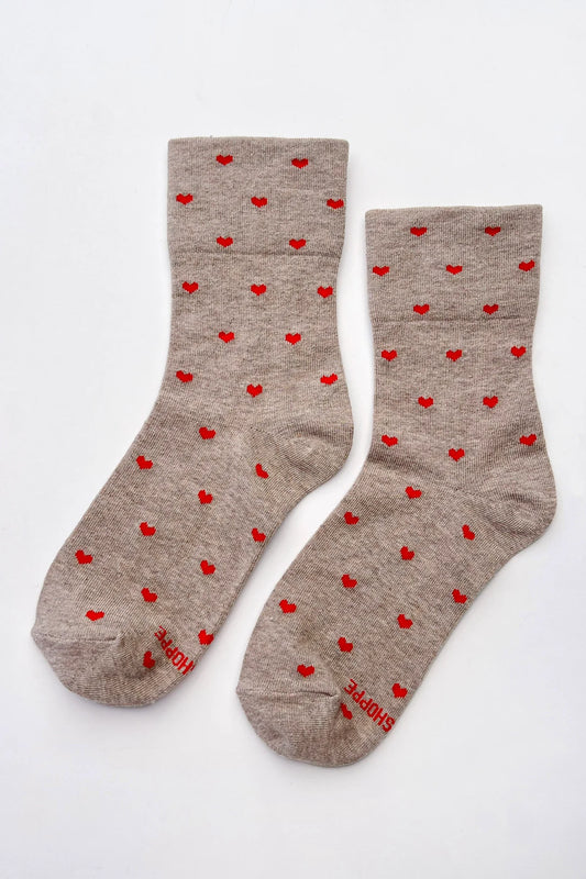 A pair of taupe heather crew socks with a repeating pattern of small red hearts, displayed flat against a clean white background.