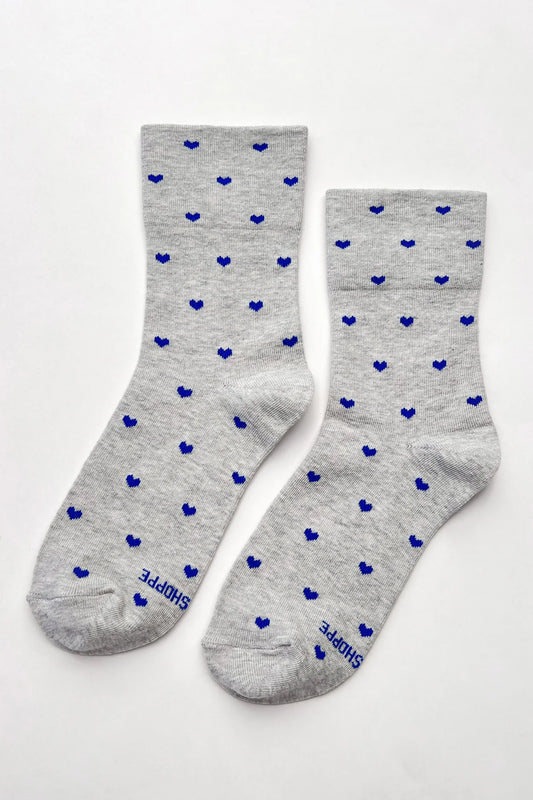 a pair of grey cotton socks with cobalt blue hearts on a white background 