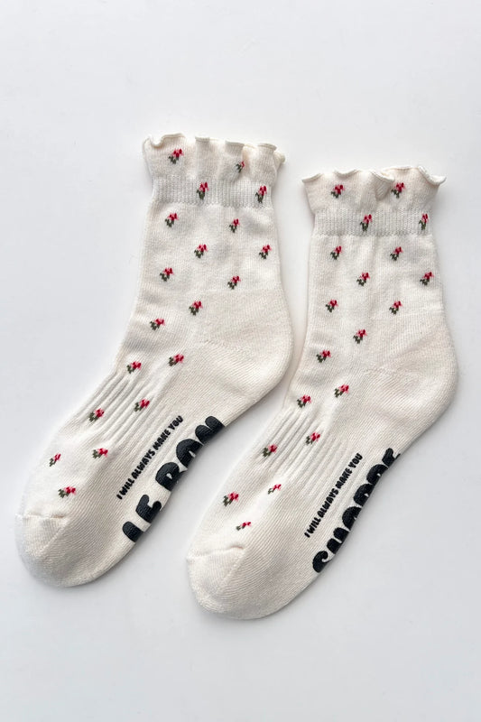 White socks with multicoloured flower print and red hearts on a light gray background