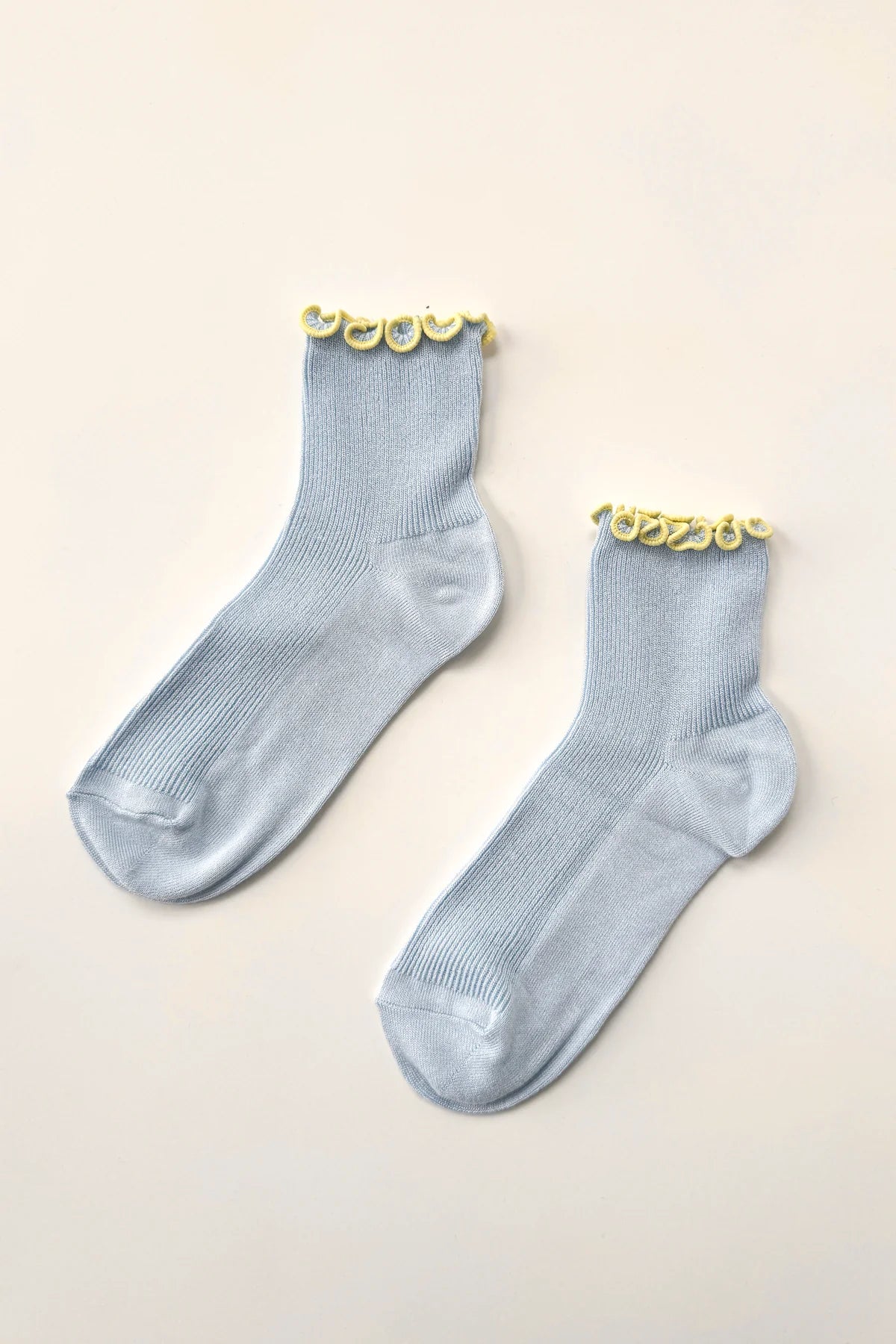 Pair of light blue socks with yellow accents on a beige background