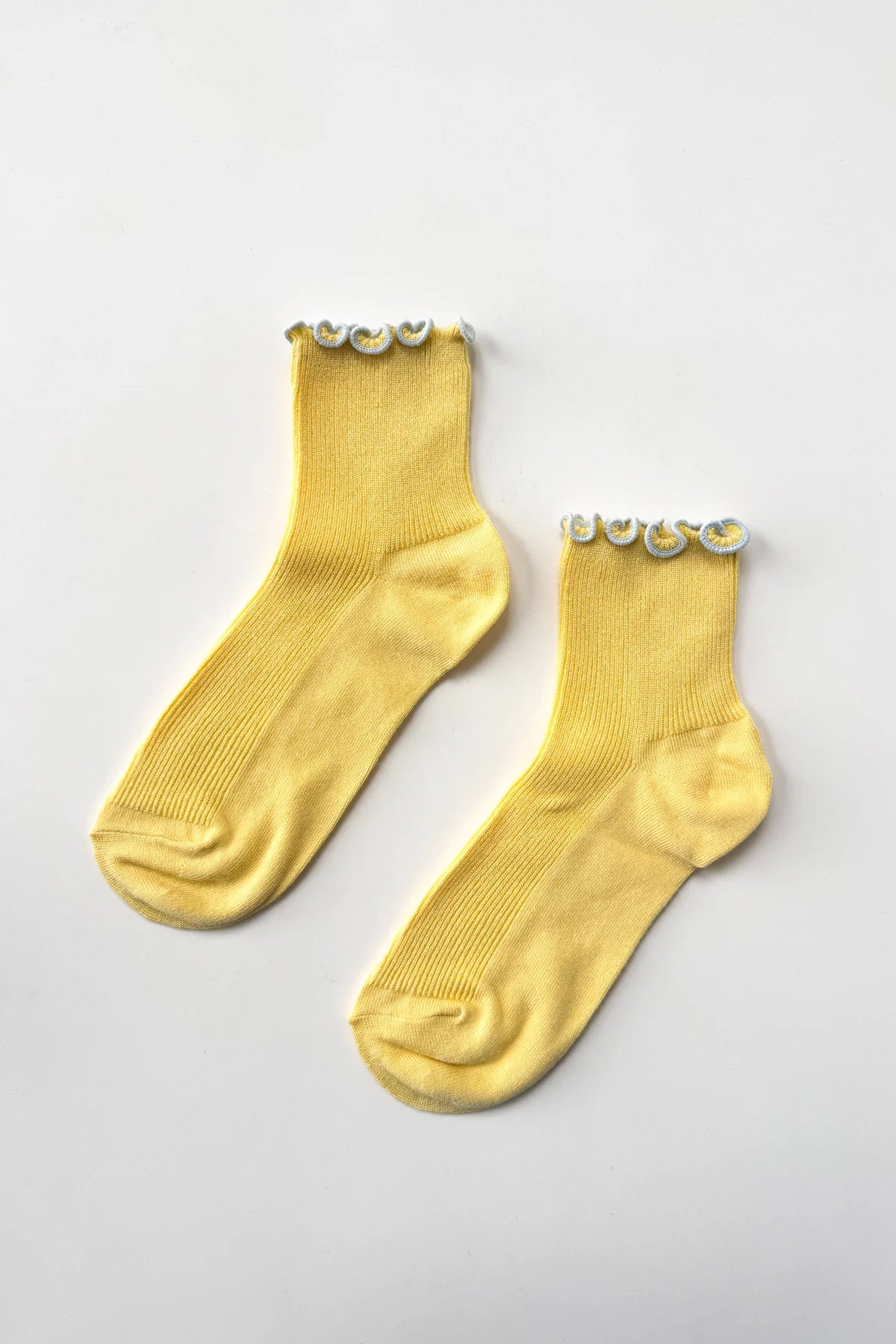 Pair of yellow socks with decorative elements on a light gray background