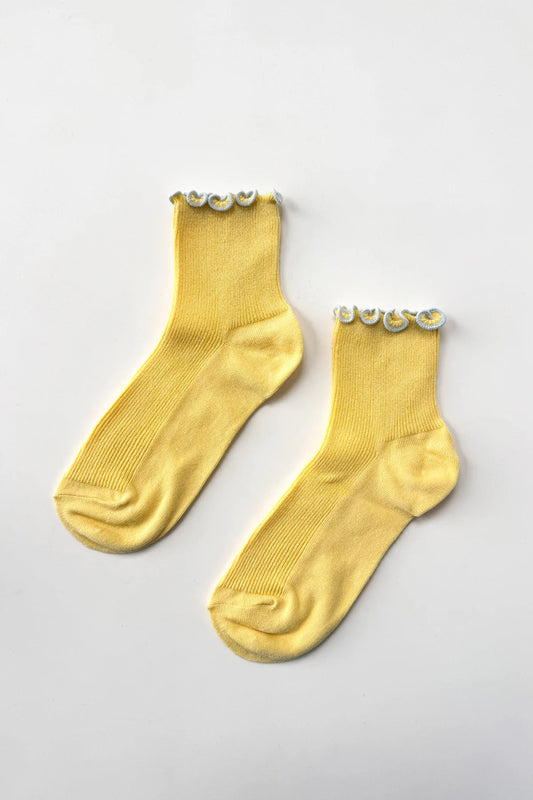 Pair of yellow socks with decorative elements on a light gray background