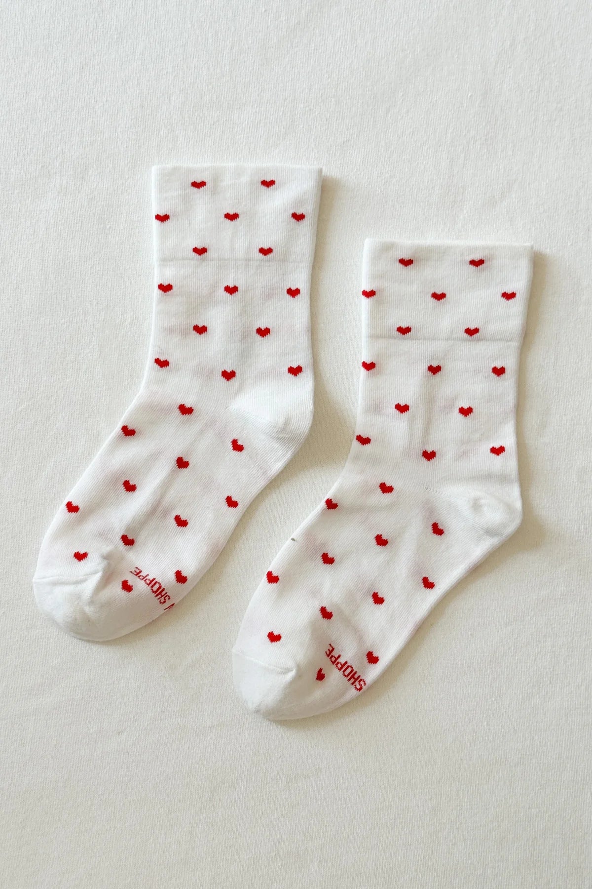 White socks with red heart patterns on a light gray background