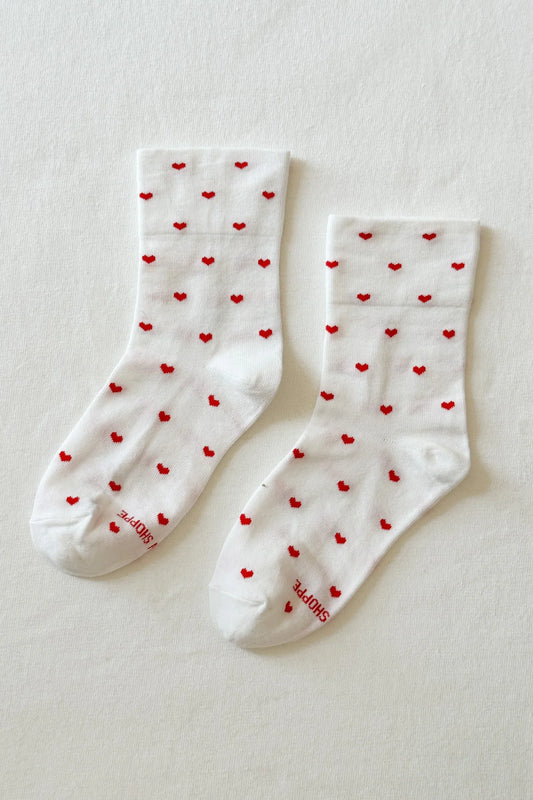 White socks with red heart patterns on a light gray background
