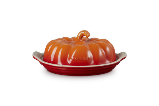 Orange ceramic butter dish shaped like a pumpkin on a white background