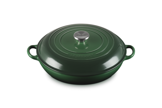 Green cast iron cookware with a lid on a white background