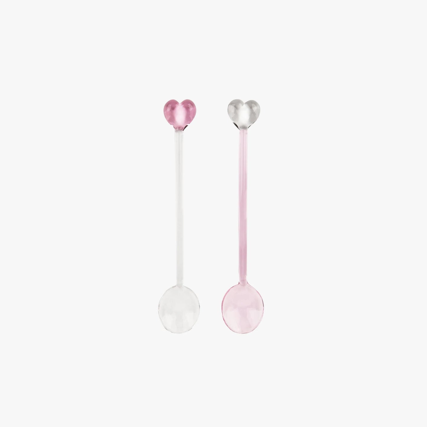 Two heart-shaped spoons, one pink and one white, on a light pink background.