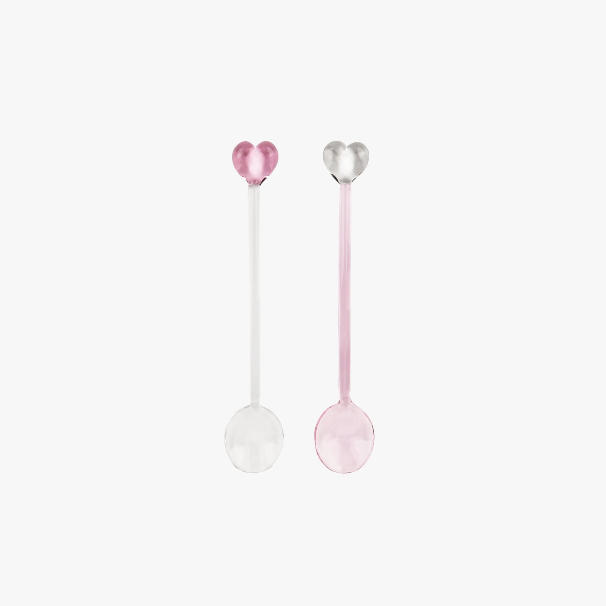 Two heart-shaped spoons, one pink and one white, on a light pink background.