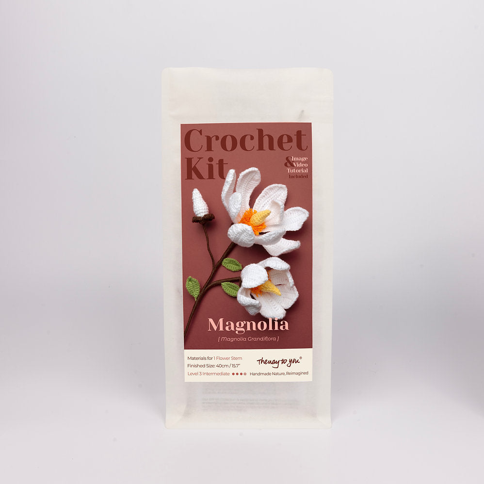Crochet kit packaging with magnolia flower design on a gray background