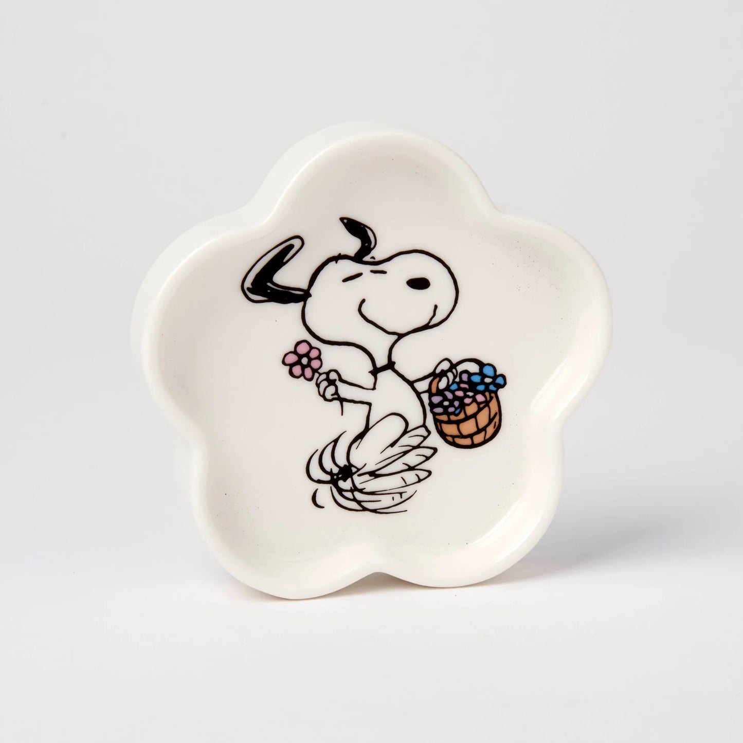 White ceramic dish with a cartoon design of a dog holding a basket and flower on a light gray background
