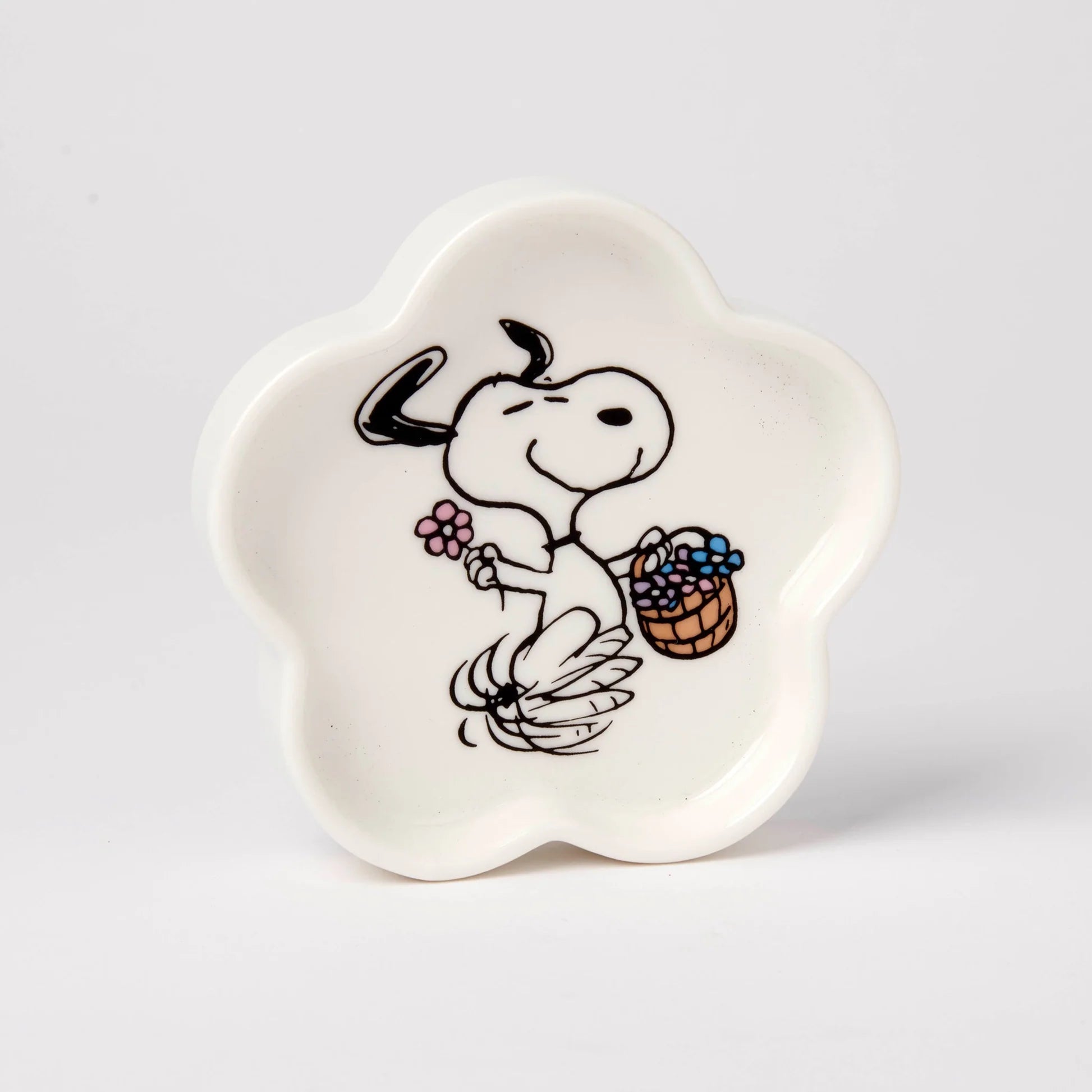 White ceramic dish with a cartoon design of a dog holding a basket and flower on a light gray background