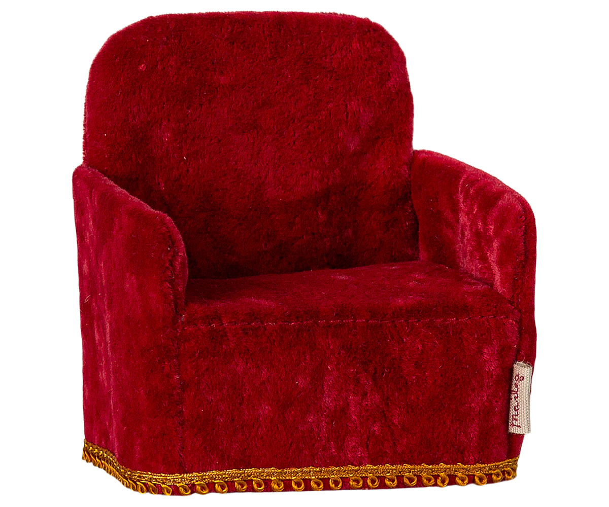 Red velvet armchair with gold trim on a white background
