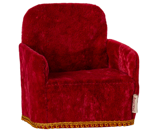 Red velvet armchair with gold trim on a white background
