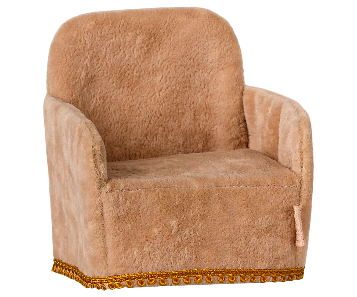 Brown plush armchair with decorative trim on a white background