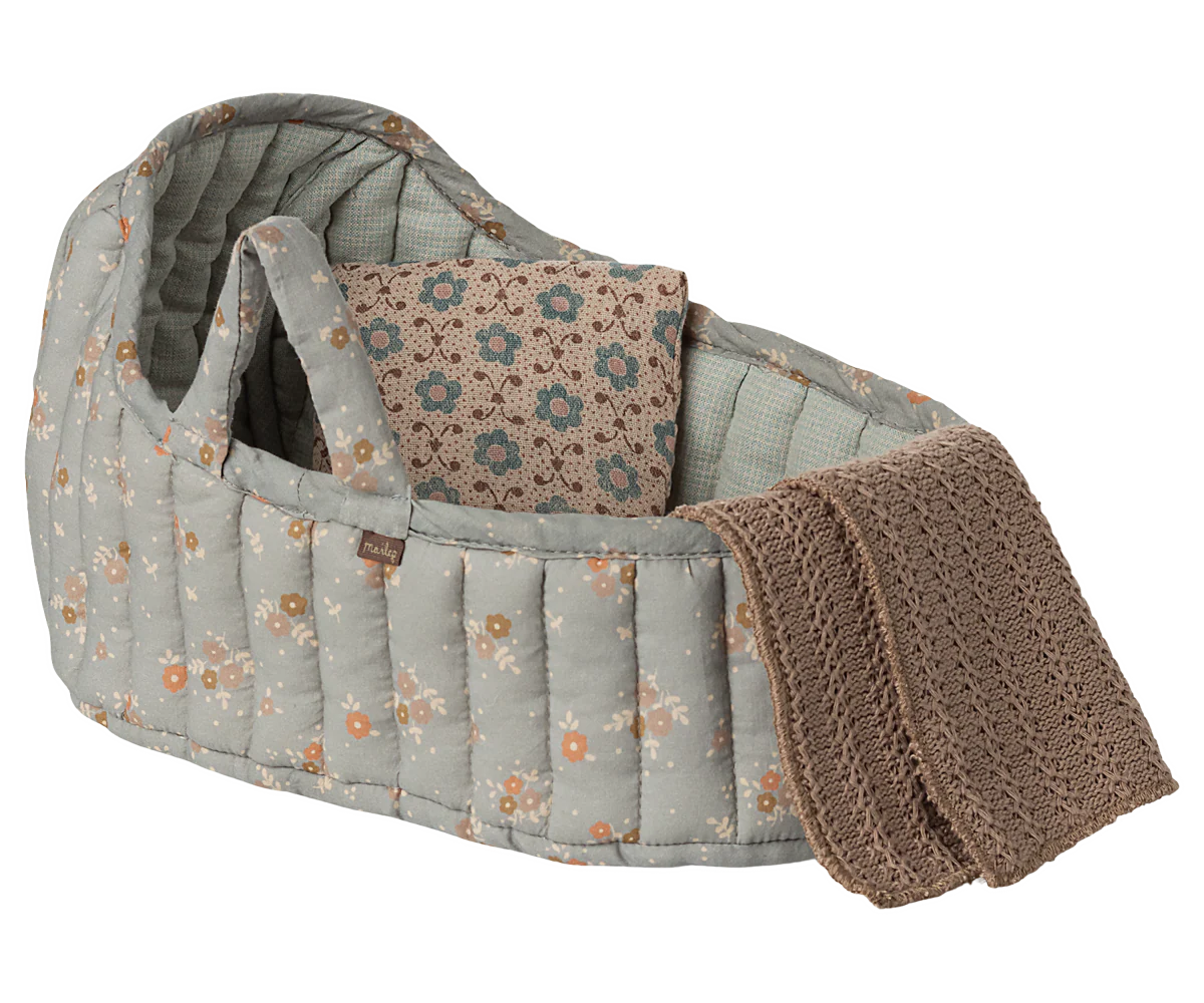 Baby crib with floral pattern and brown blanket on a white background