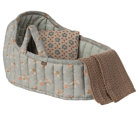 Baby crib with floral pattern and brown blanket on a white background