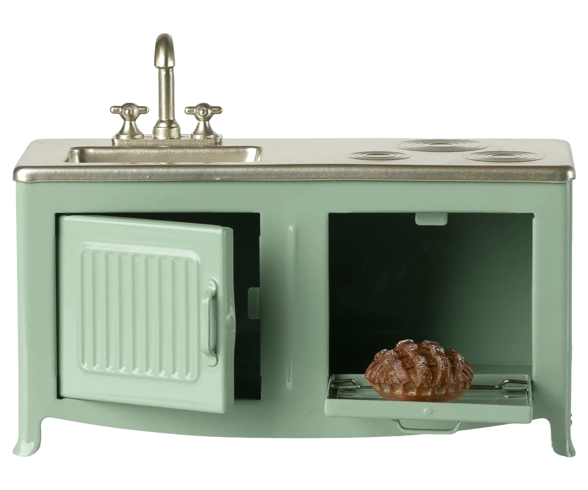 Miniature green kitchen stove with sink and oven on a white background