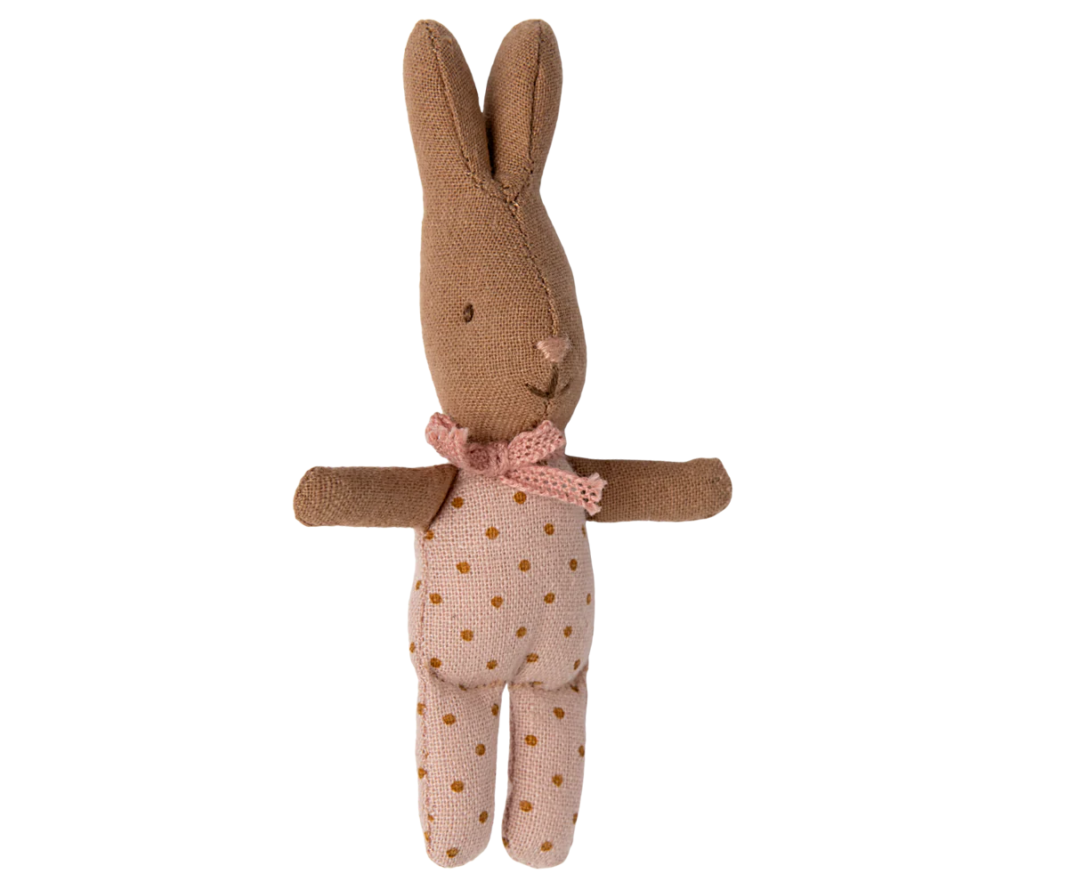 Stuffed rabbit toy with a pink bow and polka dot dress on a white background
