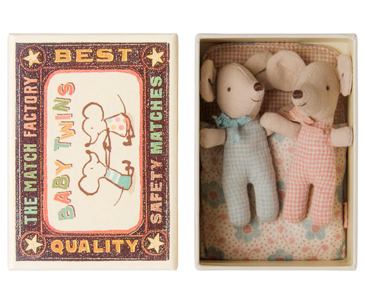 A matchbox-style gift set shown open, with the illustrated outer matchbox lid on the left and two small plush mouse toys inside the box on the right. The toys are dressed in pale blue and pale pink gingham outfits with small bows, set against a floral lining.