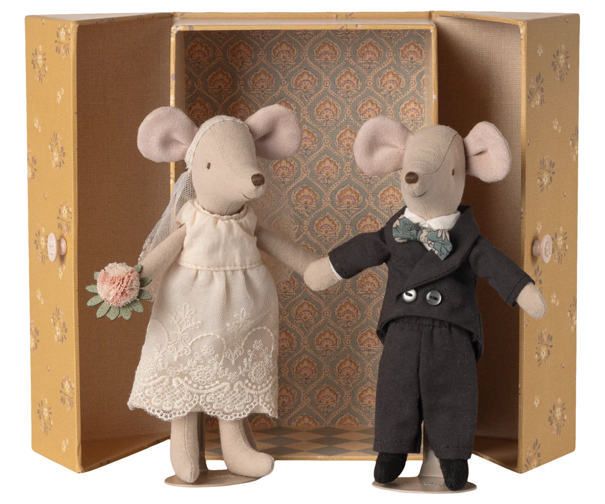 Two toy mice, one in a wedding dress and the other in a suit, standing in front of an ornate box.