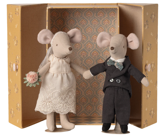 Two toy mice, one in a wedding dress and the other in a suit, standing in front of an ornate box.