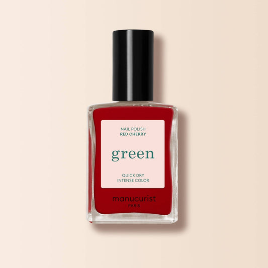 Red nail polish bottle with black cap on a beige background