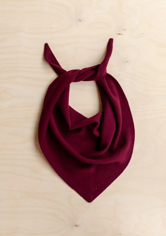 Burgundy scarf tied into a knot on a light wooden surface