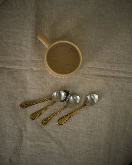 Ceramic mug and vintage spoons on a textured fabric surface