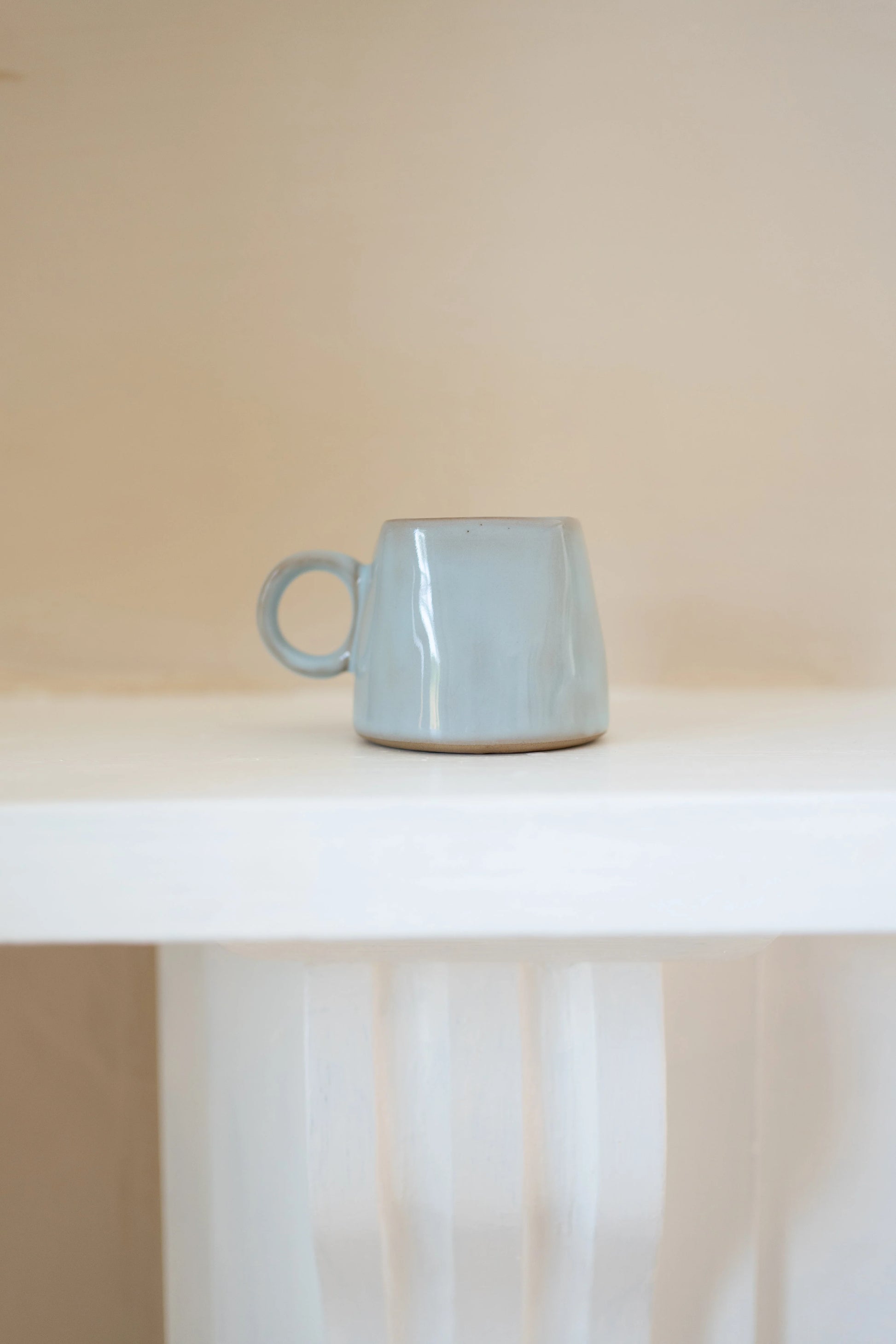 Light blue ceramic mug on a white surface with a neutral background