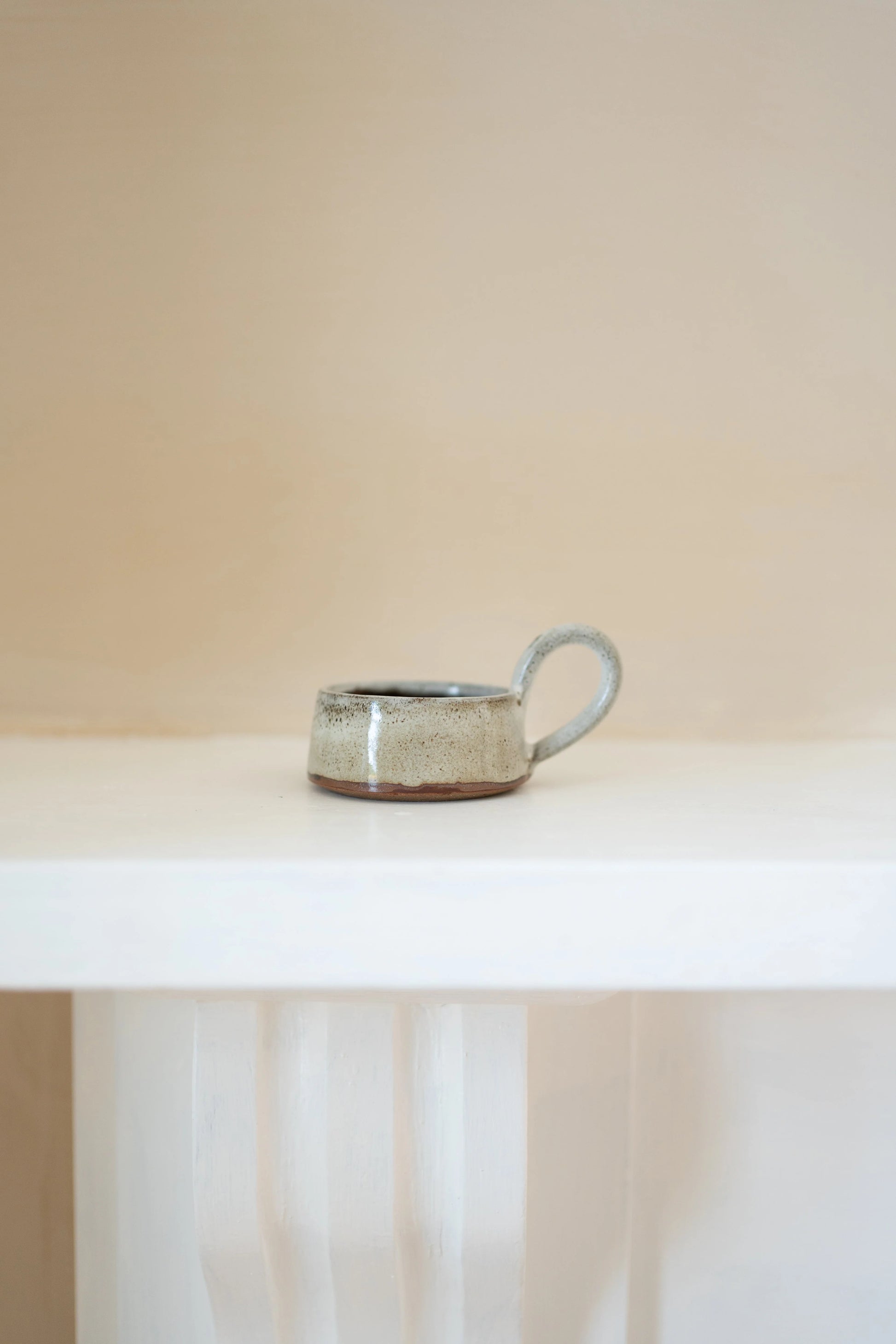 Ceramic tealight holder on a white surface with a neutral background