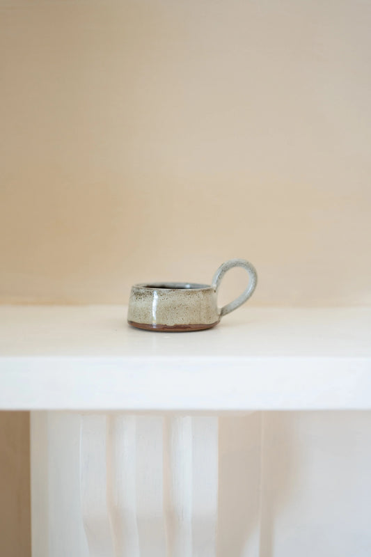 Ceramic tealight holder on a white surface with a neutral background