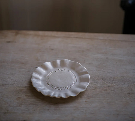 Small white ceramic plate on a wooden surface with a neutral background