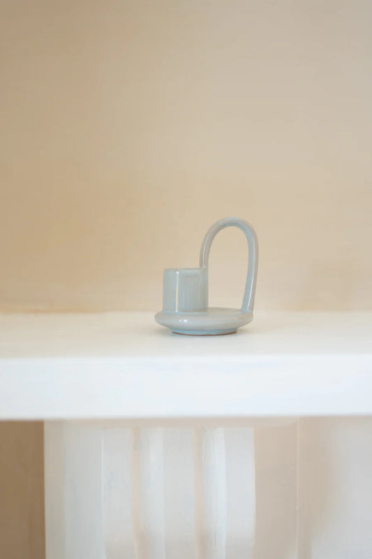 Light blue ceramic vase on a white surface with a beige background