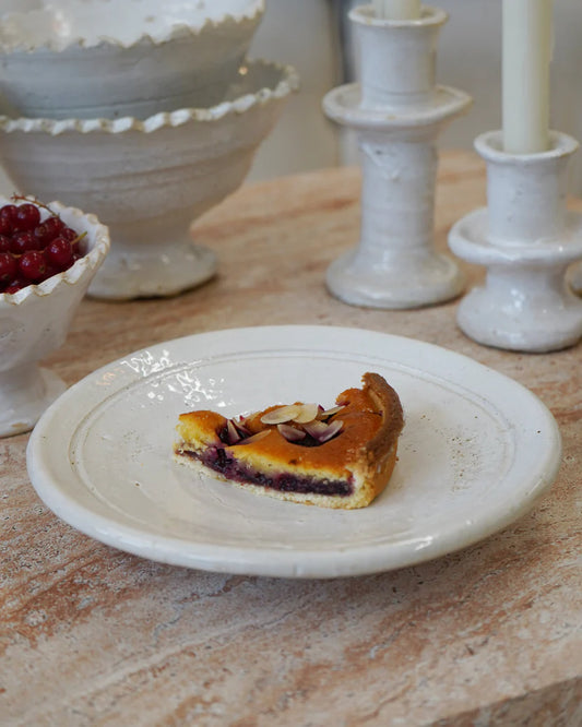 Slice of pie on a white plate with decorative bowls and candles in the background.