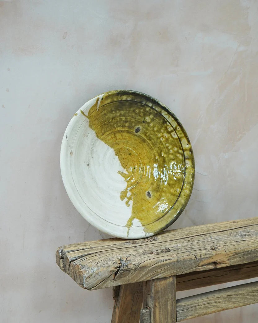 Ceramic plate with yellow/ green-ish and white design on a wooden surface
