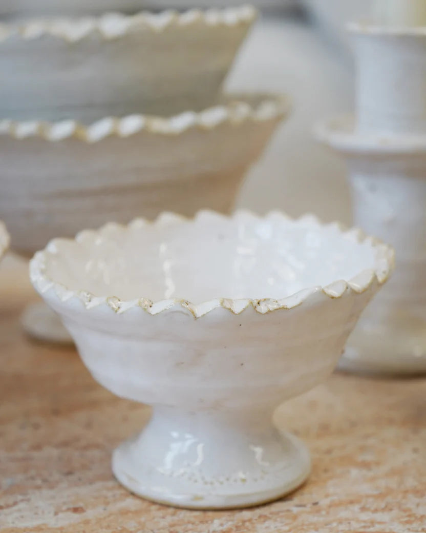White ceramic dessert stands with scalloped edges on a wooden surface