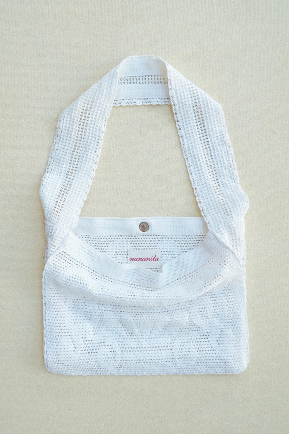 White woven handbag on a beige mannequin against a beige background