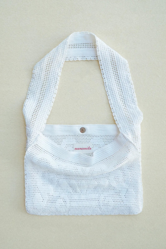 White woven handbag on a beige mannequin against a beige background
