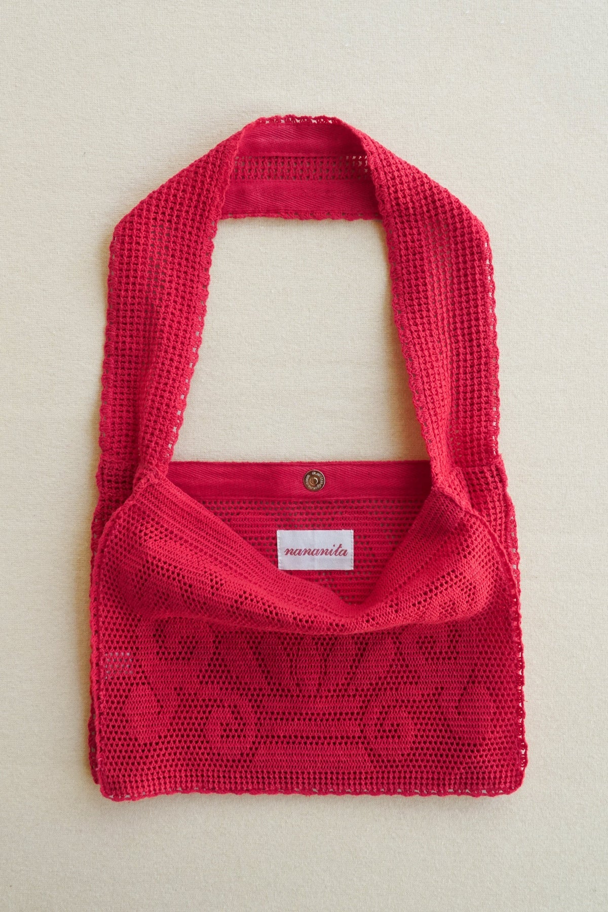 Red knitted bag with a visible brand label on a light beige background