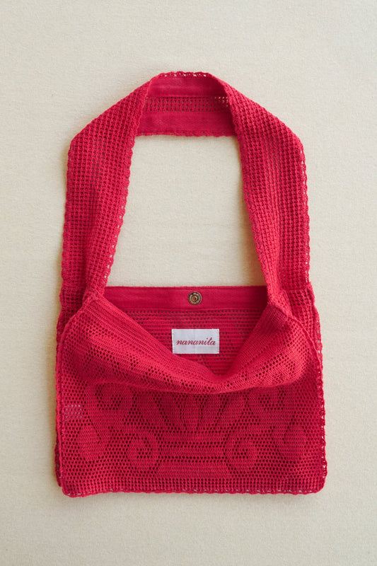 Red knitted bag with a visible brand label on a light beige background