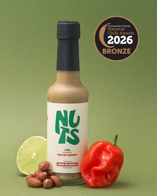 Hot sauce bottle labeled 'NUTS' with chili, lime, and nuts on a green background