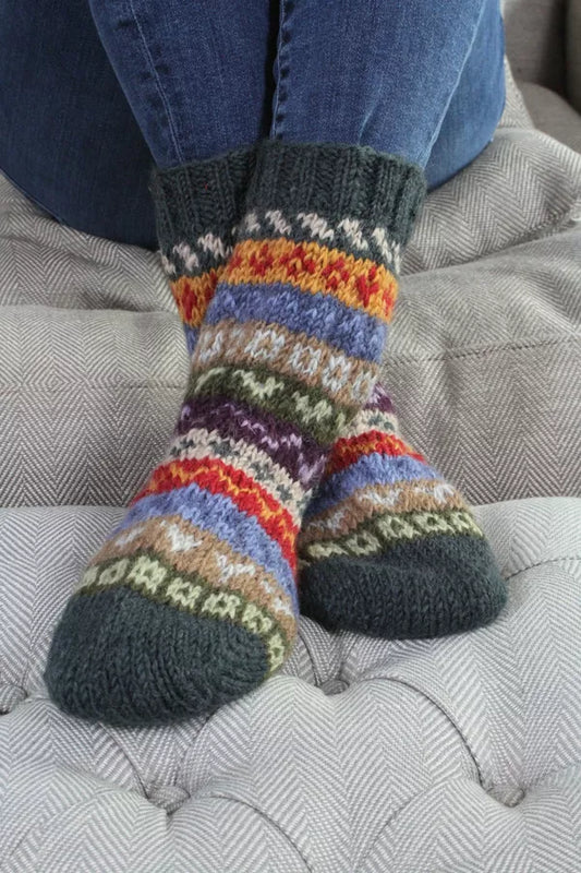 Colorful multi stripe socks worn on a gray couch