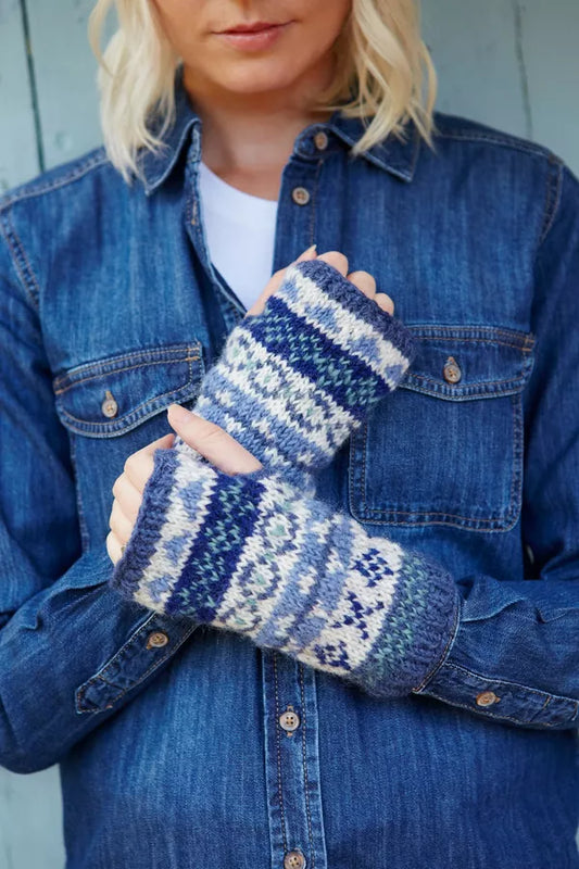 Person wearing blue denim jacket and blue patterned mittens against a light background
