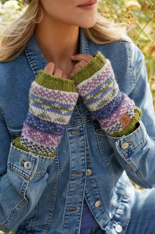 Person wearing colorful striped fingerless gloves with a denim jacket outdoors.
