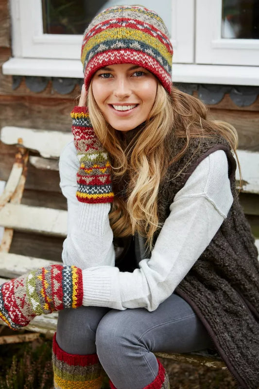 Woman wearing a colorful knit hat and gloves sitting outdoors.