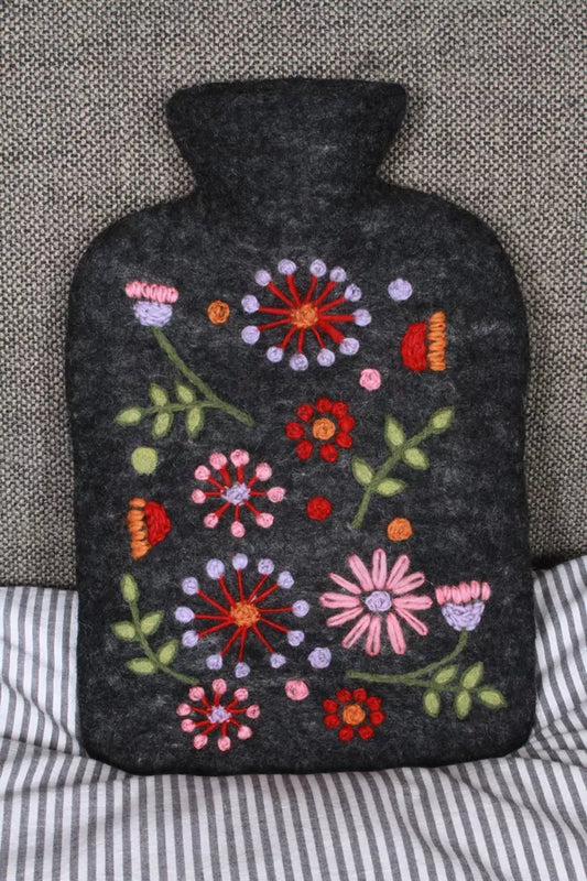 Dark gray hot water bottle cover with colorful floral embroidery on a textured surface.