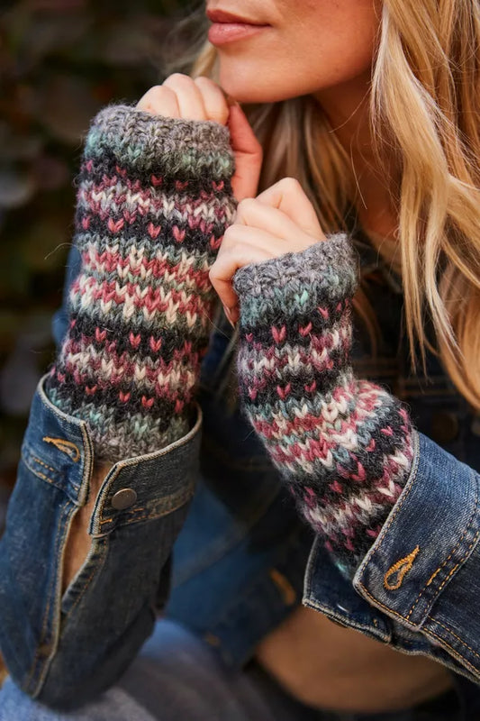 Person wearing colorful knitted fingerless gloves with a blurred background