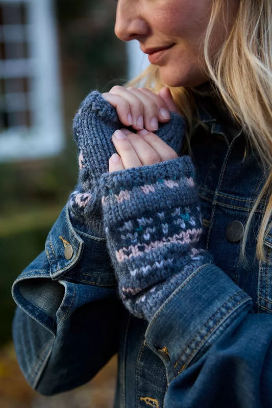 Person wearing blue knitted mittens with a blurred background