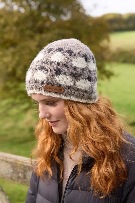 Woman wearing a patterned knit hat outdoors with greenery in the background